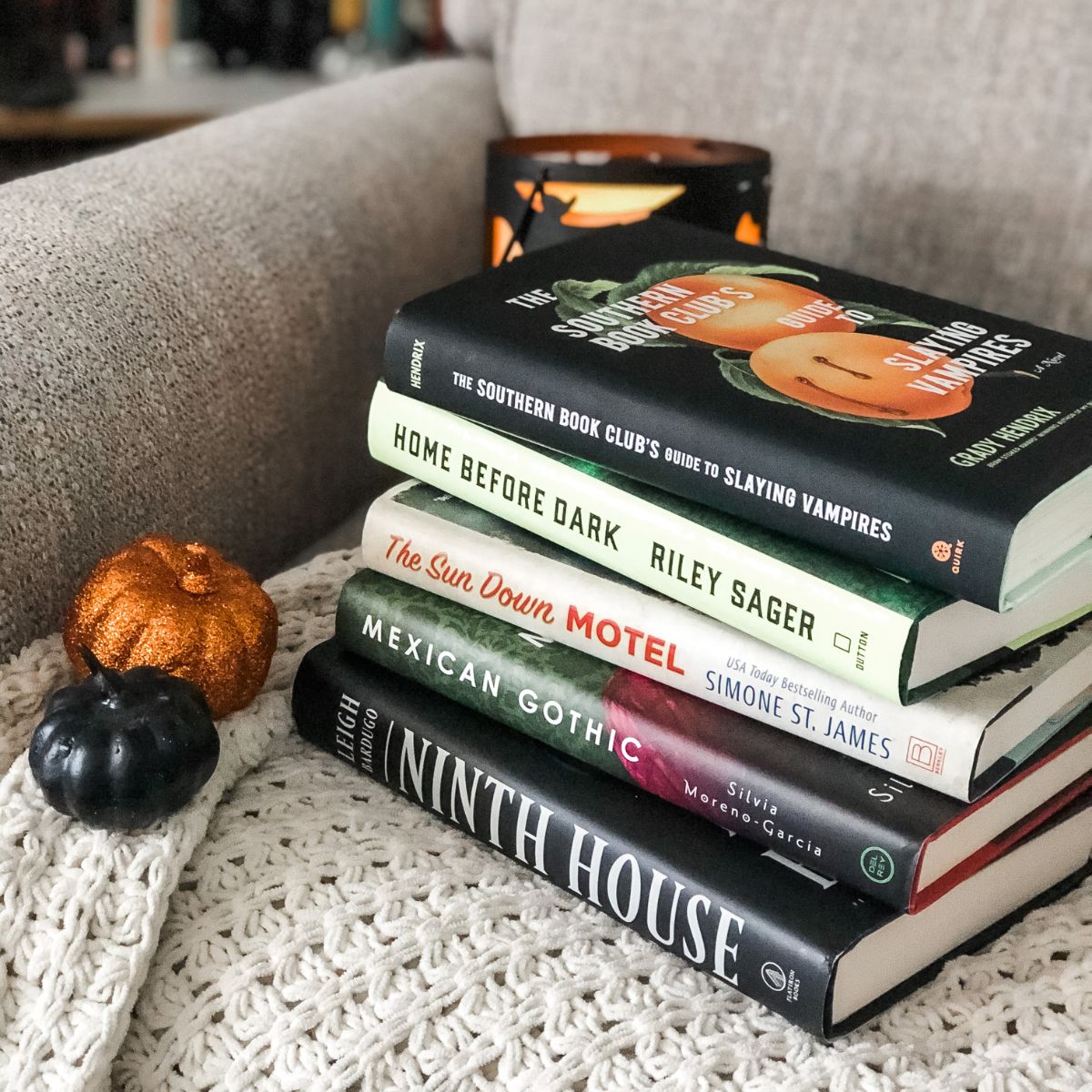 a stack of spooky Halloween books on a chair next to mini glitter pumpkins