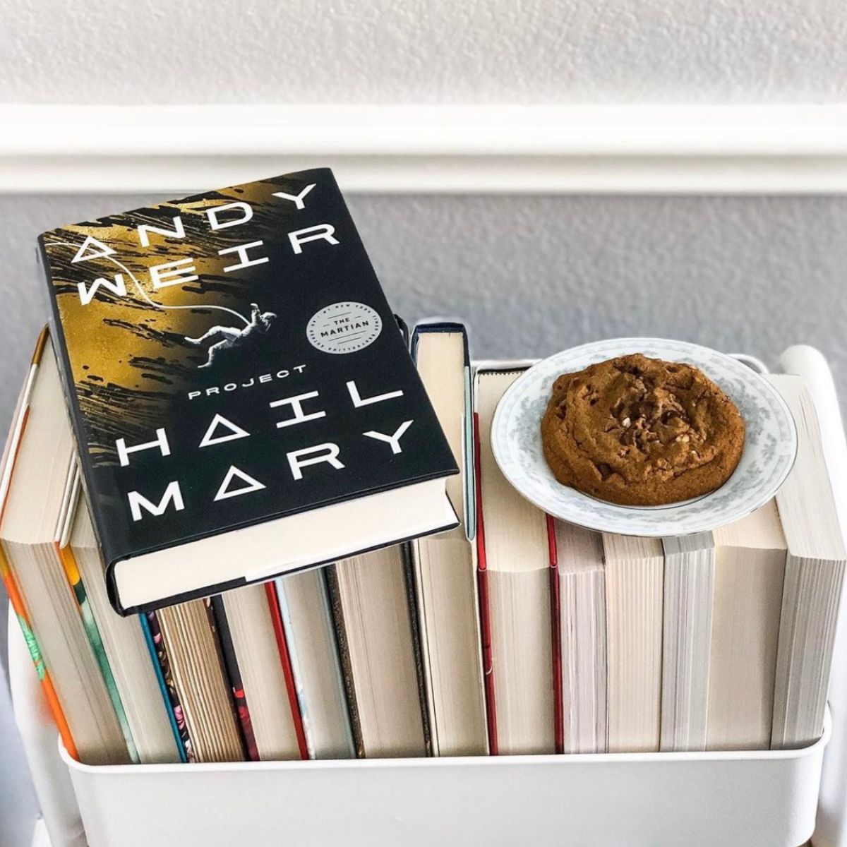 Project Hail Mary book on top of a white book cart with a cookie next to it