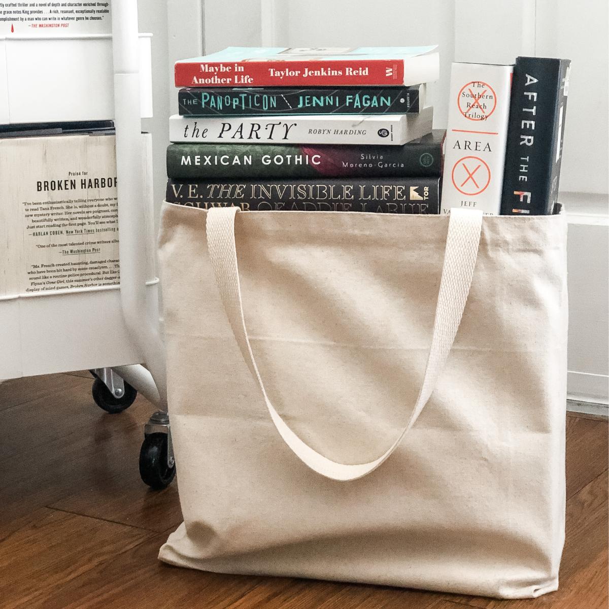 stack of secondhand books in a canvas tote bag