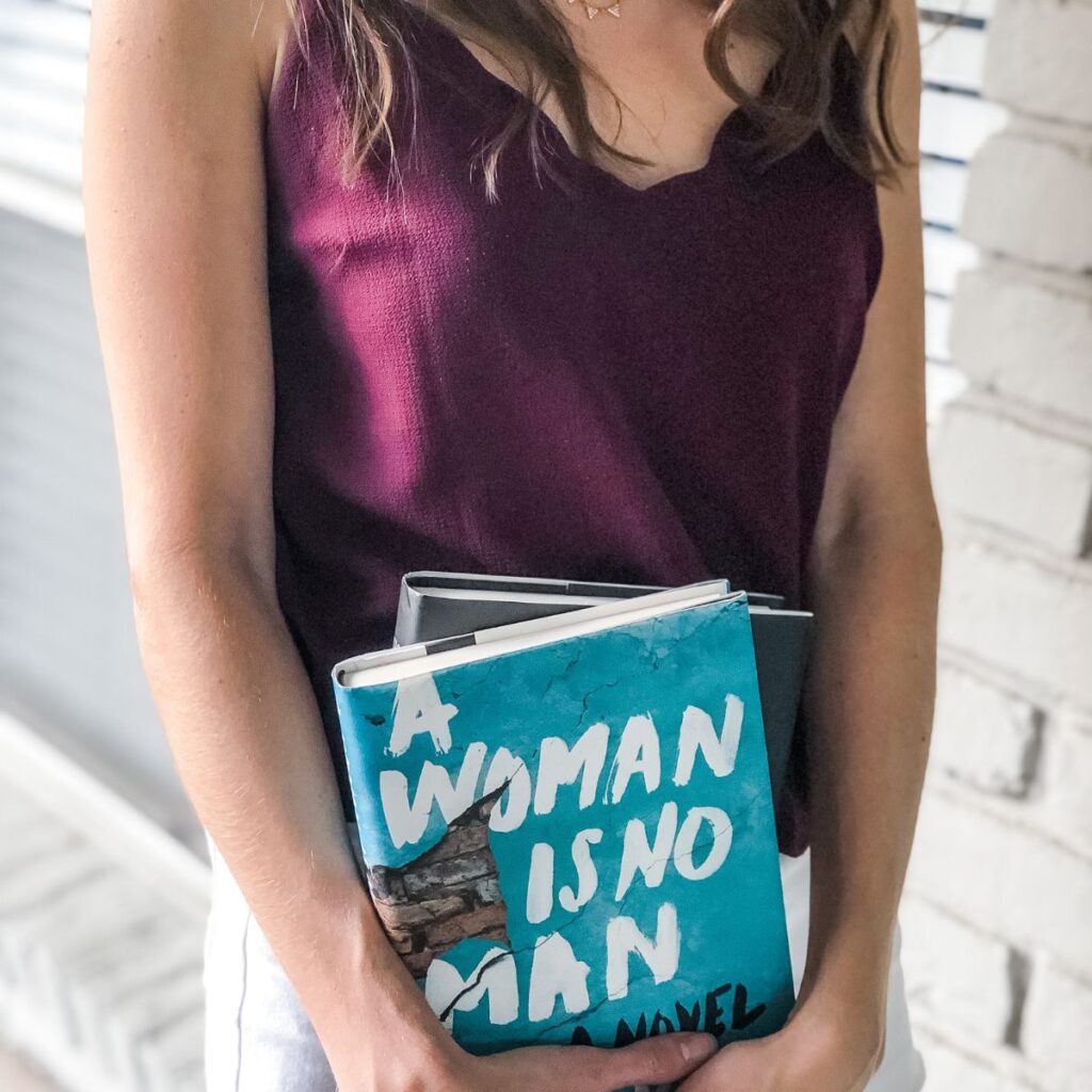 a woman wearing a purple tank top with books in her hands