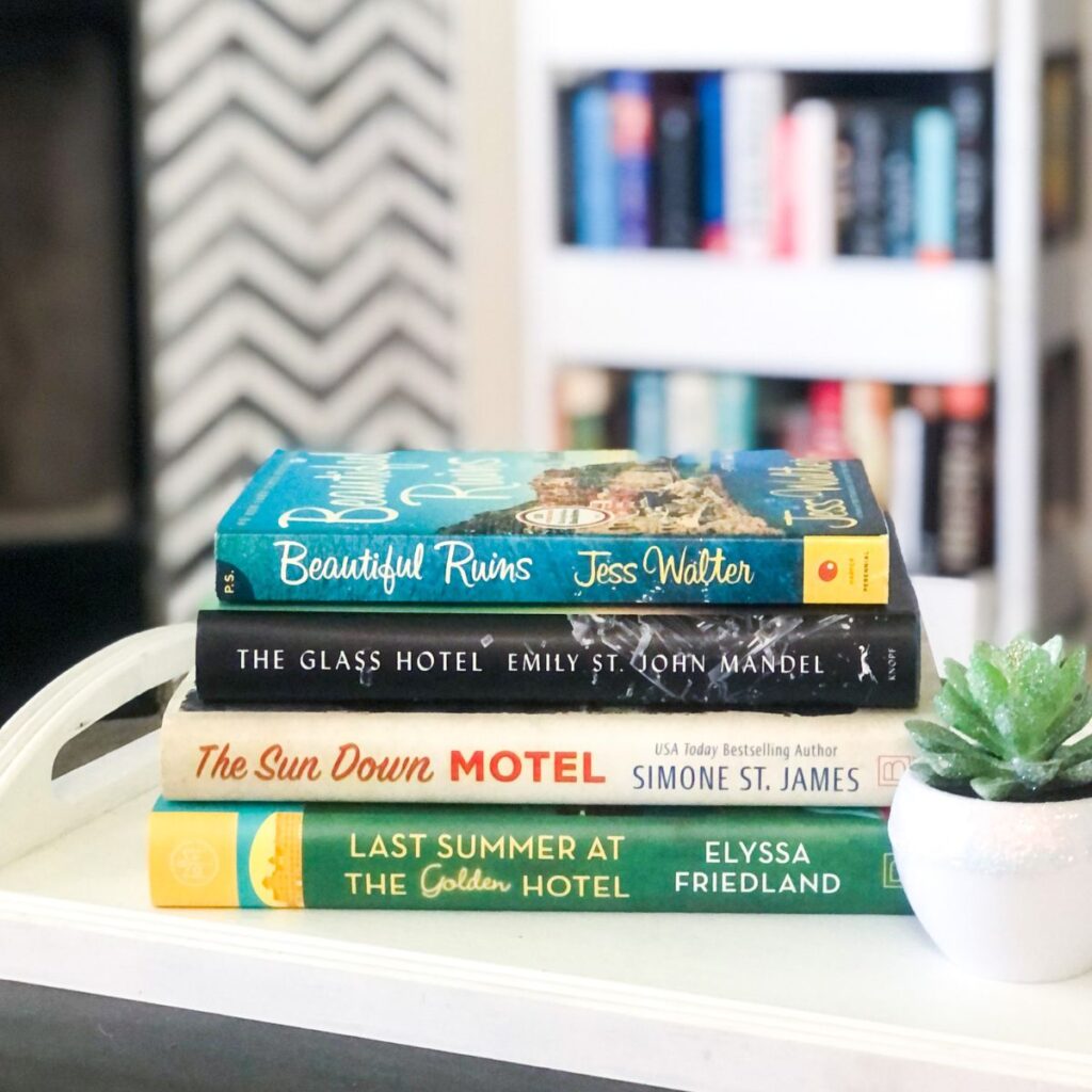 stack of hotel novels on a white wooden tray with a succulent plant beside it