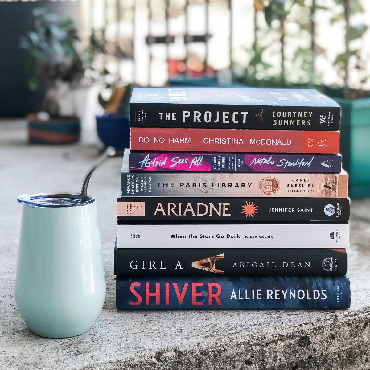 stack of books next to a teal tumbler