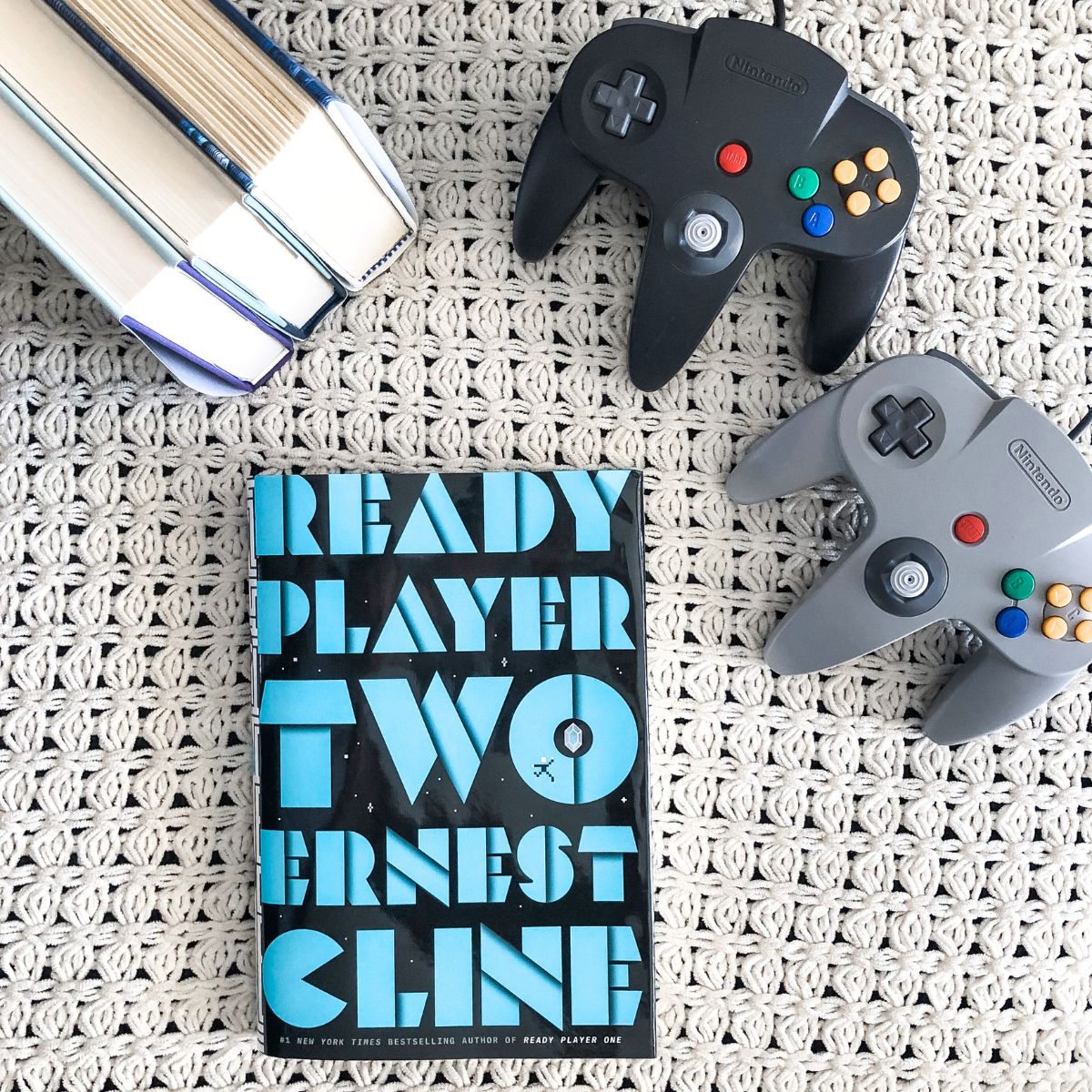 fiction books about video games with Nintendo 64 controllers on a white blanket