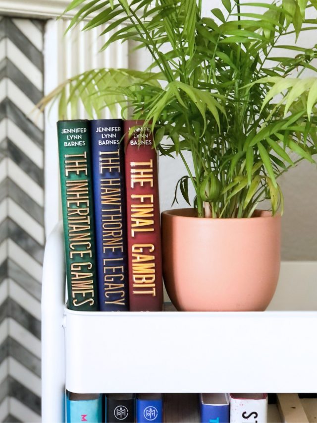 The Inheritance Games books on a book cart with a plant
