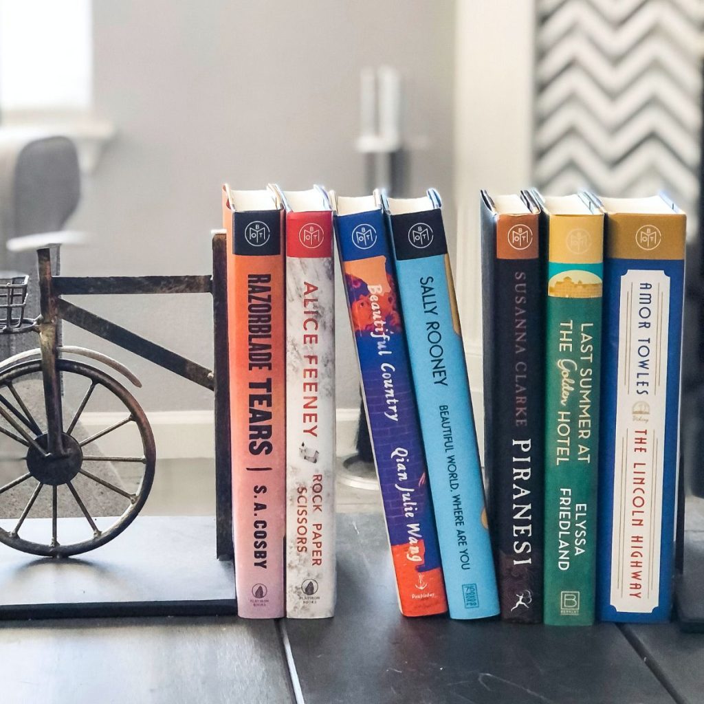 Book of the Month books  leaning against a bookend on a coffee table