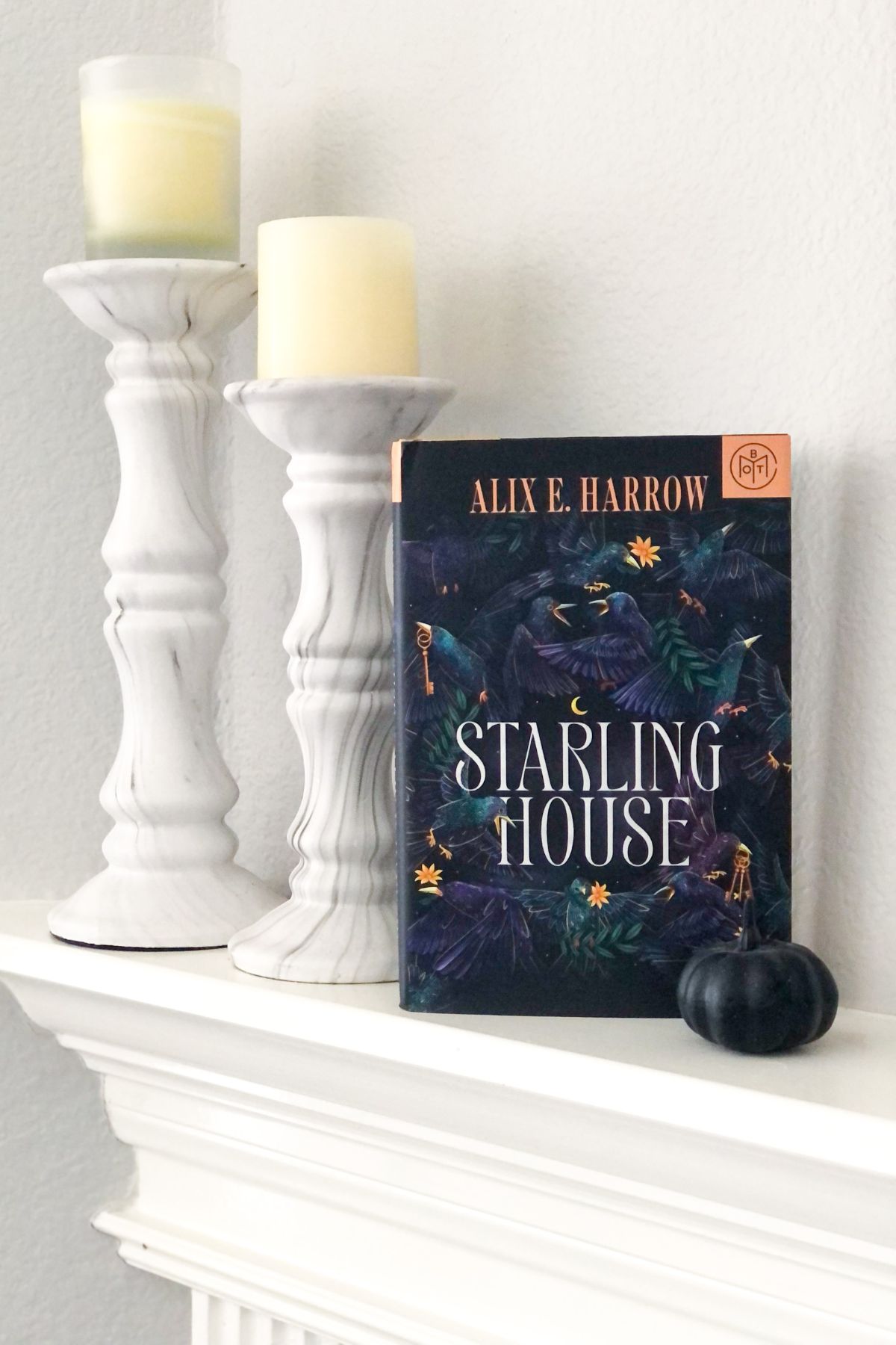 Starling House hardcover book with a black pumpkin and candles on a white fireplace mantel