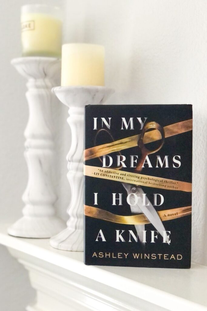 In My Dreams I Hold a Knife hardcover book on a fireplace mantel with candles